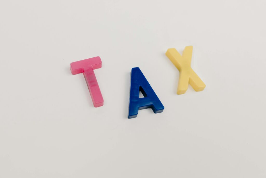 Colorful plastic letters spelling tax on a clean white background.