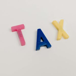 Colorful plastic letters spelling tax on a clean white background.